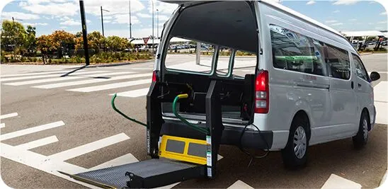 A white Toyota HiAce maxi taxi with its rear wheelchair lift deployed, ready for a long-distance trip across WA.