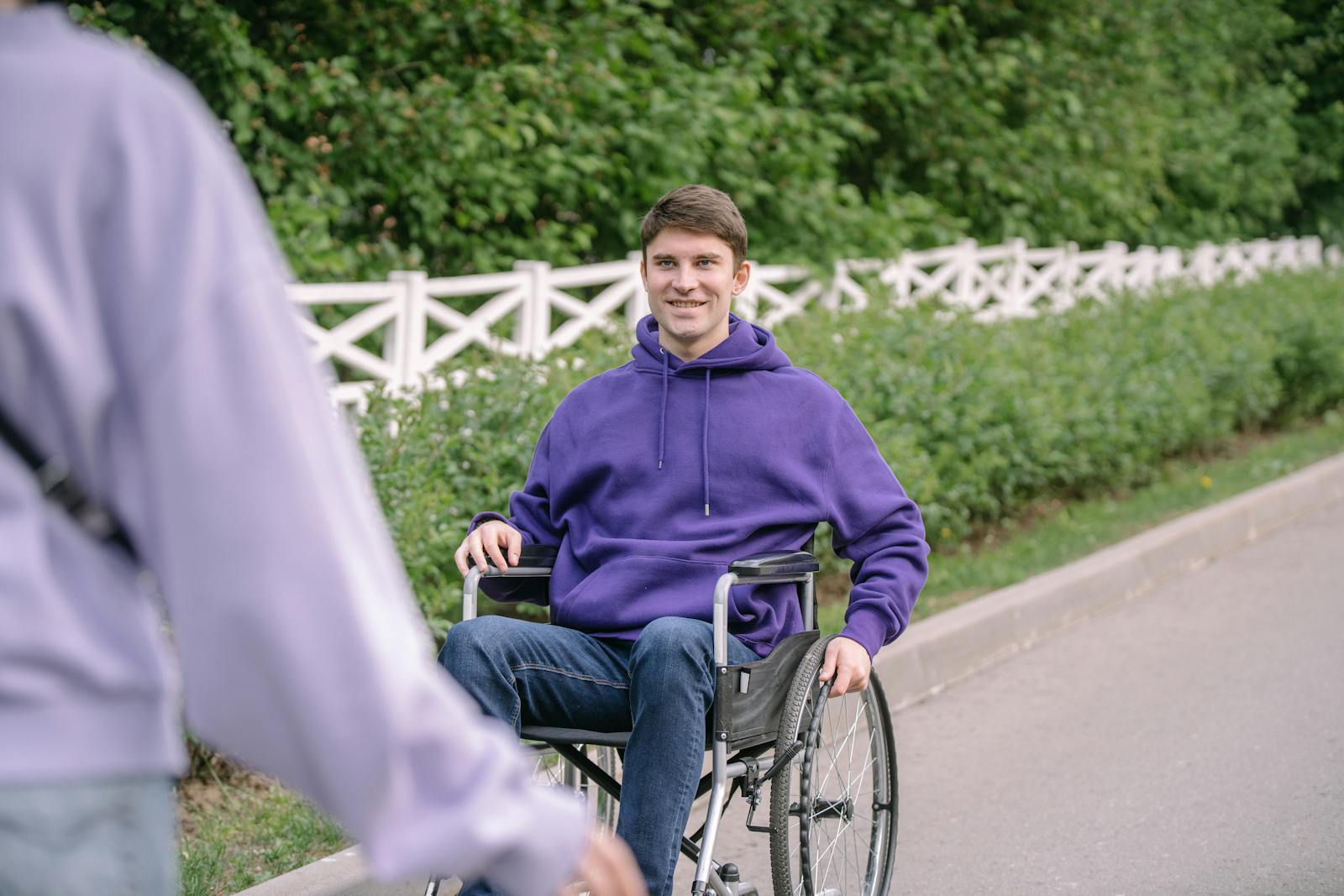 A smiling NDIS participant who uses a wheelchair, out in the community.